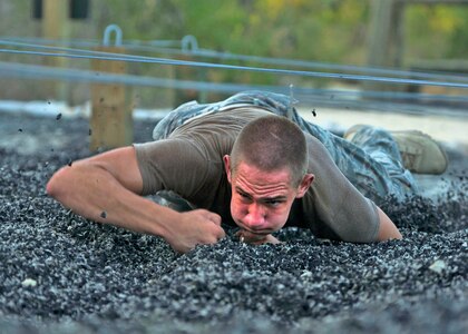 An Air Force pararescue trainee low crawls during an obstacle course event at the Lackland Training Annex Aug. 18. The initial course for a Pararescueman trainee is a nine-week extensive physical conditioning indoctrination program at Lackland. The program includes physiological training, obstacle course, marches, dive physics, dive tables, metric manipulations, medical terminology, cardiopulmonary resuscitation, weapons qualifications, PJ history and leadership reaction course. (U.S. Air Force photo/Senior Airman Erik Cardenas)