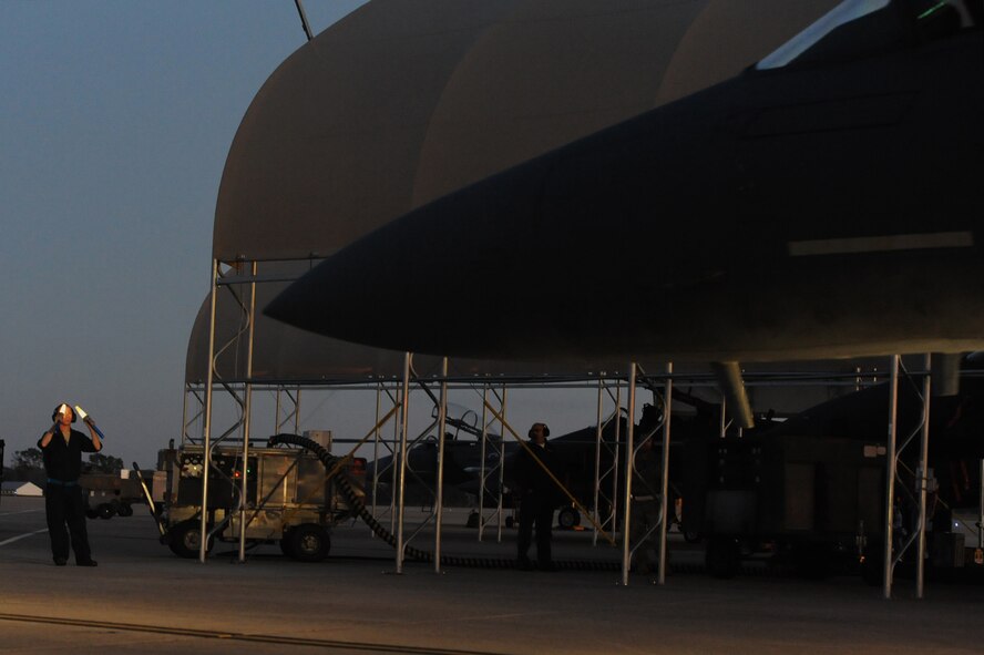 Senior Airman Trever Diimmel marshals an F-15E Strike Eagle out of its shelter during a launch assist on Seymour Johnson Air Force Base, N.C., Oct. 25, 2011. Launching a jet requires a minimum of two people, one person signals the aircrew and the other removes the chocks. Diimmel is a 4th Aircraft Maintenance Squadron crew chief and hails from Auburn, Wash. (U.S. Air Force photo by Senior Airman Whitney Stanfield)
