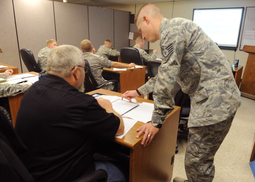Staff Sgt. Kelby Mier, 7th Logistics Readiness Squadron, Hazmat Tech Specialist instructor, assists Mr. Brian Claassen, 317th Maintenance Squadron, during a course Oct. 27, 2011, at Dyess Air Force Base, Texas. Each individual is hand selected from their shop to take the course in order to gain authorization to sign-off on hazardous materials. (U.S. Air Force photo by Airman 1st Class Cierra Bullock/Released)