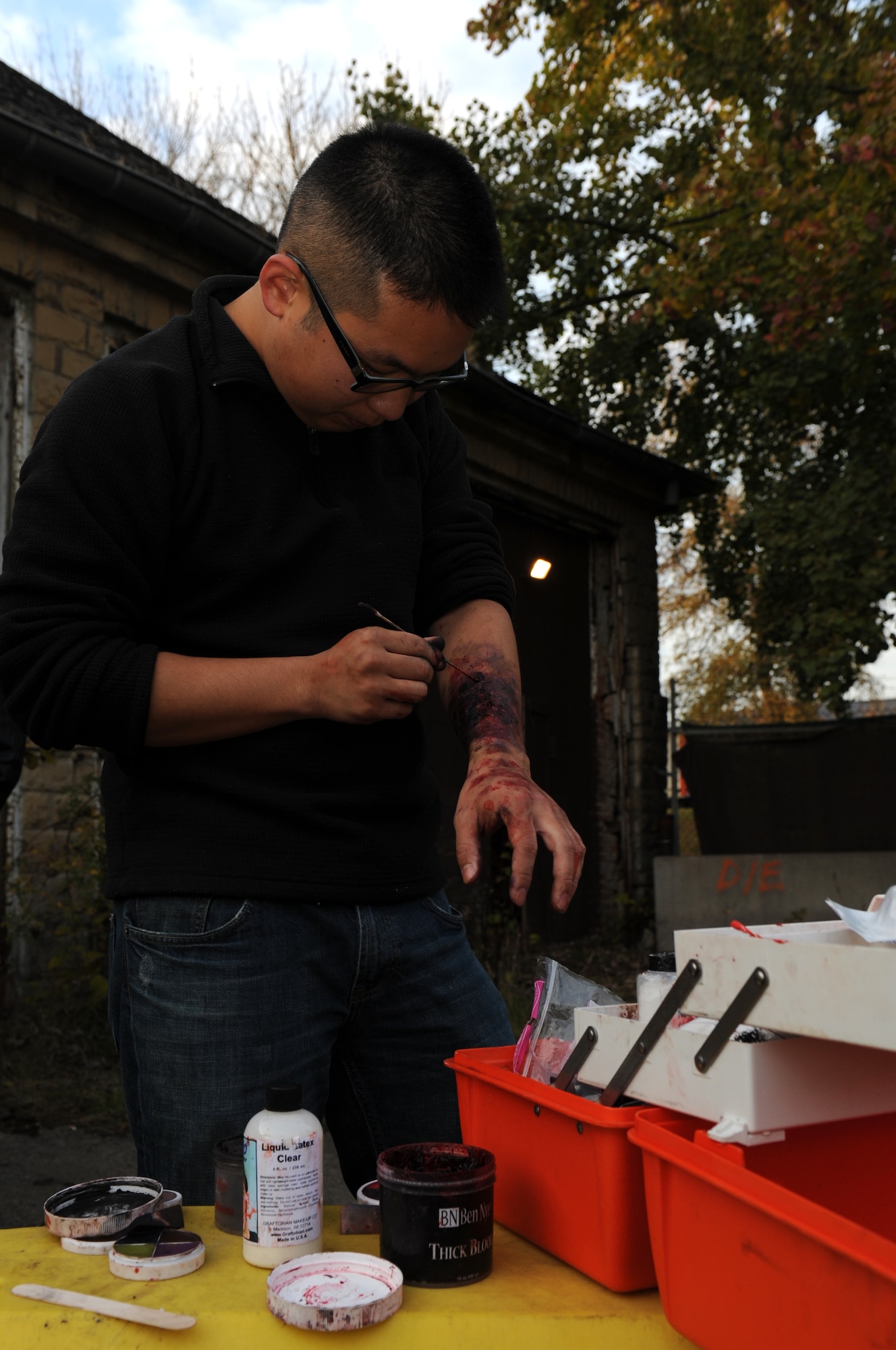 BITBURG ANNEX, Germany -- Senior Airman Sung Hwang, 52nd Medical Operations Squadron aerospace medical technician, paints a wound to his arm for a haunted house here Oct. 27. The haunted house is scheduled for Oct. 27-29 in Bldg. 2032 and 2033 at the French Casern on Bitburg Annex. Admission is $5 for adults and $3 for children younger than 13. The doors open at 5 p.m. every night. The first hour of the night is for younger children who just want to trick-or-treat. (U.S. Air Force photo/Airman 1st Class Brittney Frees)