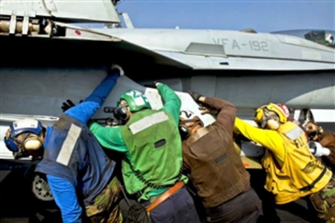 U.S. Navy sailors push an F/A-18C Hornet  in position on the flight deck aboard the aircraft carrier USS John C. Stennis in the Arabian Sea, Oct. 23, 2011.