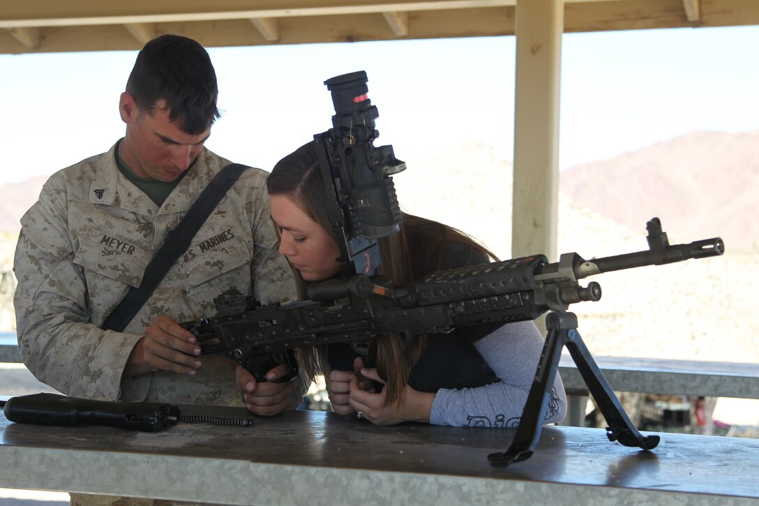Cpl. Zackary Meyer, a rifleman with Company B, 1st Battalion, 7th Marine Regiment, helps his wife Crystal, properly load an M240G machine gun during the unit’s Jane Wayne Day Oct. 29, 2011.::r::::n::