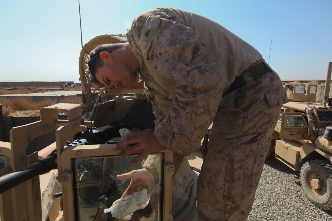 Cpl. Joel Emmert, the armory mentor with Embedded Partnering Team, 2nd Marine Logistics Group (Forward), cleans the windows of his vehicle's turret in preparation for another day of travel in a convoy, Oct. 30. Emmert aided in escorting the newly trained Afghan National Army soldiers of 215th Corps Logistics Battalion last week from Kabul to Camp Shorabak in Helmand province.