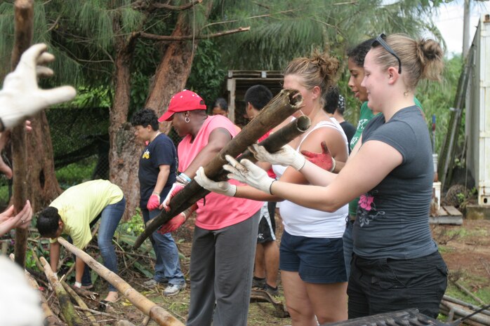 Marines and sailors from Marine Aviation Logistics Squadron 12, Marine Fighter Attack Squadron 115 and Strike::r::::n::Fighter 94 Squadron load bamboo sticks and other debris onto the bed of a pickup truck here at the Island Girl Power club Oct. 29. The IGP has worked in conjunction with service members to provide young girls an opportunity to see a more active role within their communities and combat may issues that girls many have in the region.