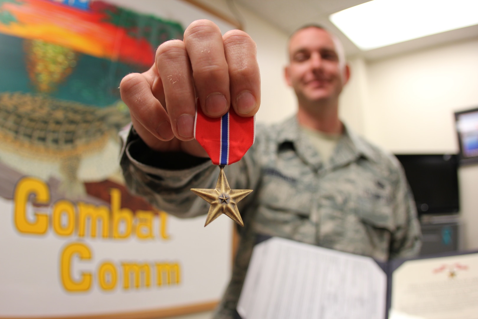 Staff Sgt. Stephen Herron reviews his Bronze Star medal and citation in the 52nd Combat Communications Squadron front office. Herron was presented the medal at a 689th Combat Communications Wing field commander's call, Oct. 31. Herron received the award for his efforts during his seven month deployment in support of forward deployed EOD teams. (U.S. Air Force photo/Robert A. Talenti)