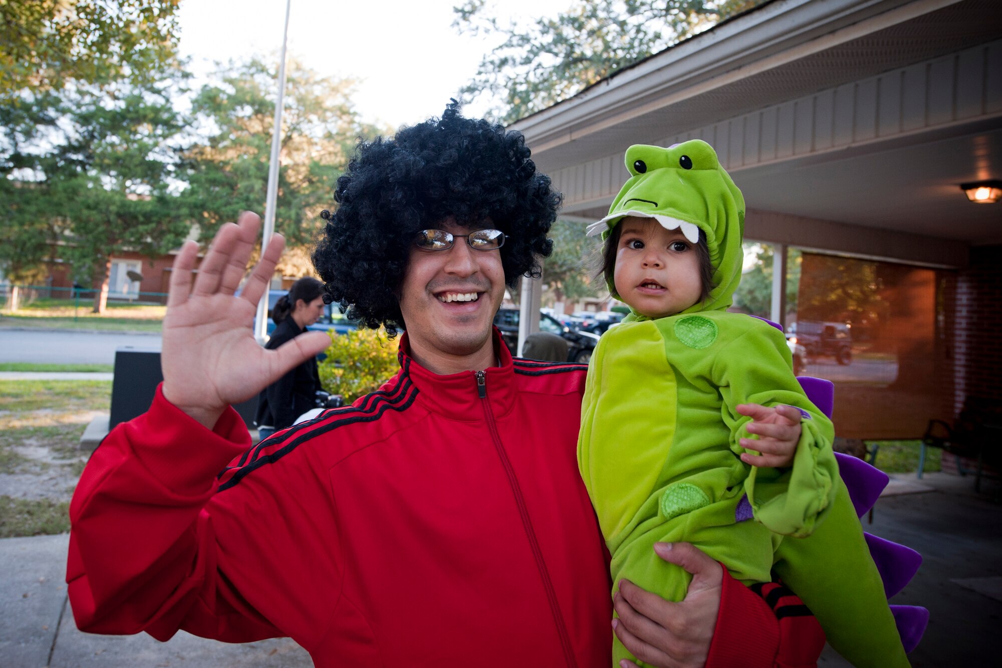 U.S. Air Force Staff Sgt. Edward Diaz, 23rd Equipment Maintenance Squadron, and his daughter, Elaina, wave at the camera during trick or treat at Moody Air Force Base, Ga., Oct. 29, 2011. Moody held trick or treat from 6 to 8 p.m. at Quiet Pines base housing. (U.S. Air Force photo by Staff Sgt. Jamal D. Sutter/Released)
