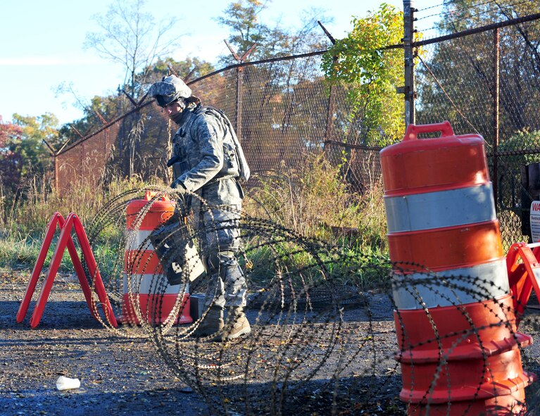 U.S. Air Force Airman 1st Class Sergio Maturana, 105th Security Forces Squadron fire team member, secures the entry control point after a vehicle leaves the field training exercise site at Camp Smith, N.Y., Oct. 28, 2011. Maturana has never deployed and this was his first time training with the 823rd Base Defense Squadron. (U.S. Air Force photo by Staff Sgt. Stephanie Mancha/Released)