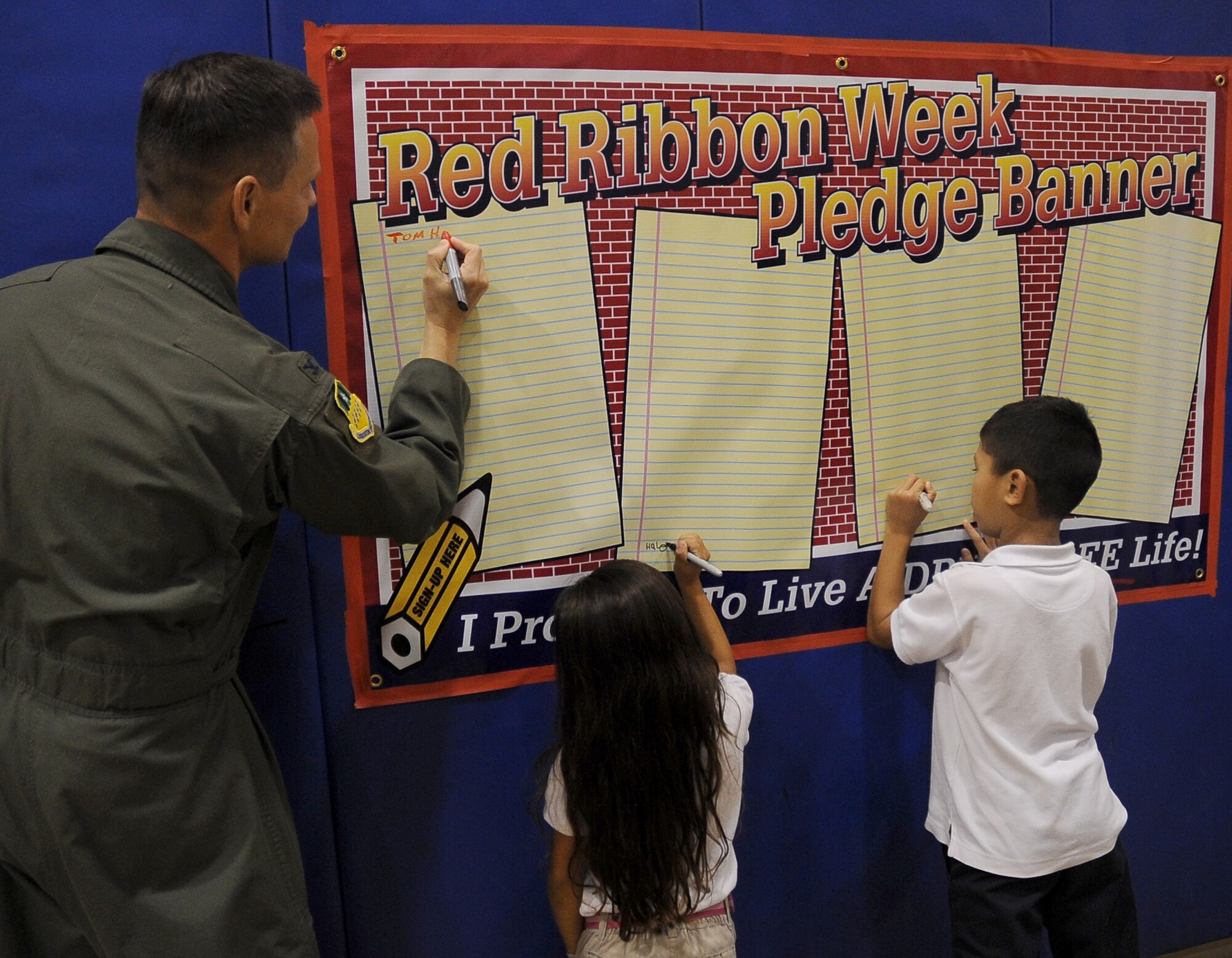 Col. Thomas Hesterman, 2nd Bomb Wing vice commander, signs the Red Ribbon Week pledge banner with children at the Youth Center on Barksdale Air Force Base, La., Oct. 27. Red Ribbon Week was held to bring awareness about drugs to Barksdale youth and parents. More than 50 children attended the final event and signed the pledge against doing drugs. (U.S. Air Force photo/Senior Airman Amber Ashcraft)(RELEASED)
