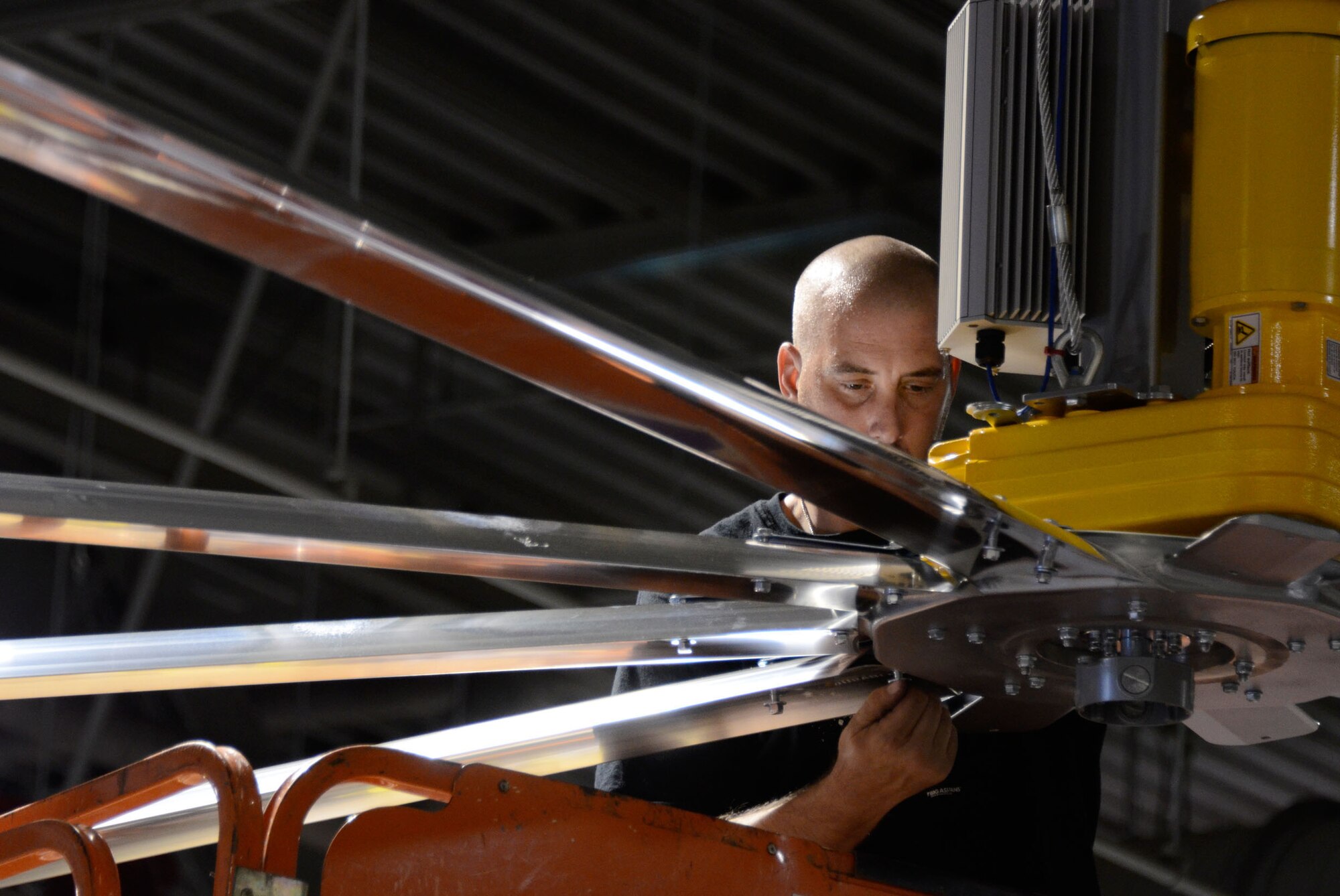 A member of the installation crew secures the fan blades of large 24-foot fans mounted on the ceiling of bay 3 in the maintenance hangar here Oct. 27. (U.S. Air Force photo/Don Peek)