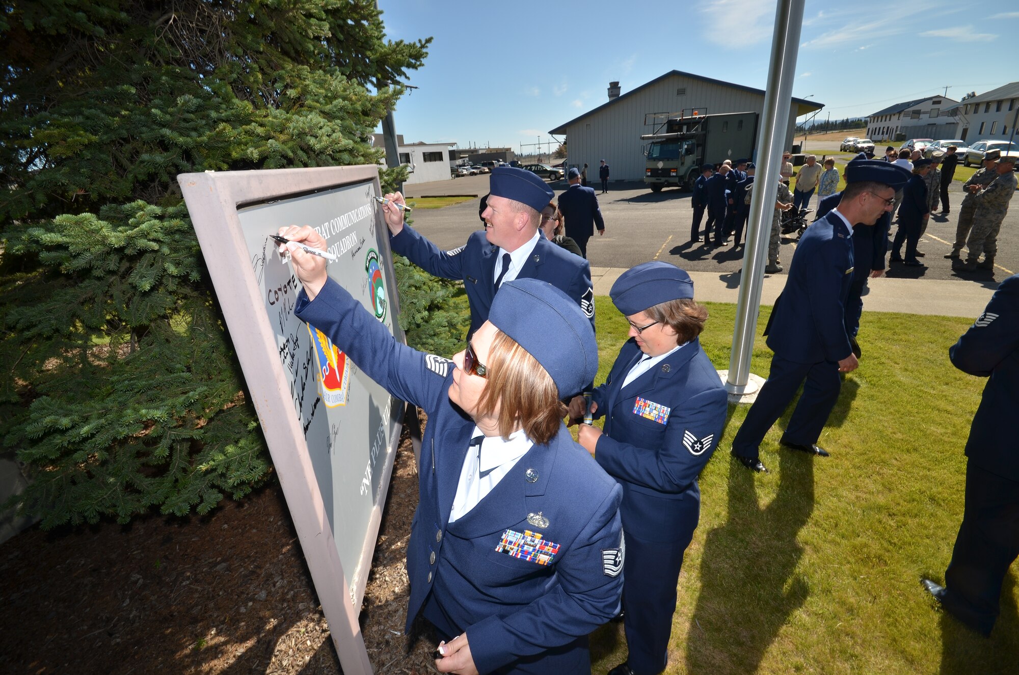 Members of the 242 Combat Communications Squadron write their names on the
squadron sign at the conclusion of the ceremony.