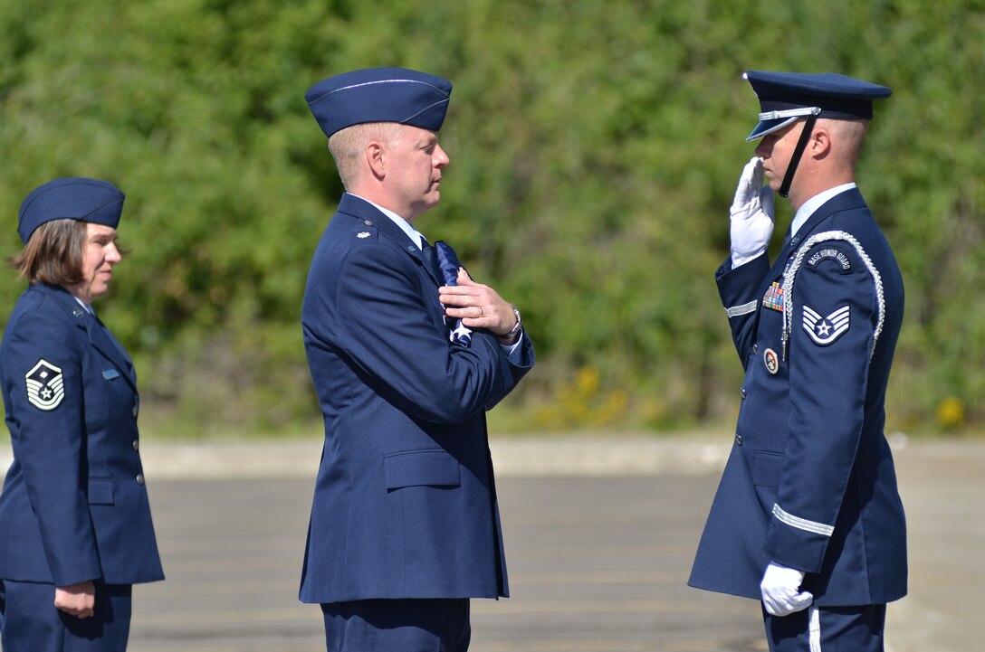Lt. Col. Casey McGinn, commander of the 242 Combat Communications Squadron, receives the lowered flag from Staff Sgt. Johnny Enis of the 141st Air Refueling Wing Honor Guard.