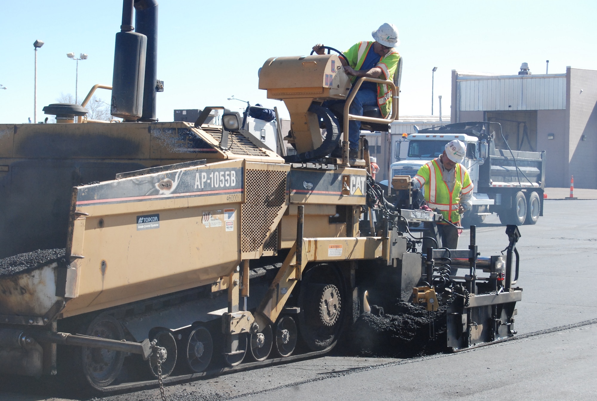 Construction workers lay down asphalt for the parking lot behind the Logistics Readiness Squadron building. The asphalt is a mix of recycled asphalt shingles, recycled concrete, rock and sand, and reduces waste sent to landfills. The recycled shingles and concrete come from the local area. The remnants of the old parking lot are being used in other projects around base. (U.S. Air Force photo/Lea Johnson)