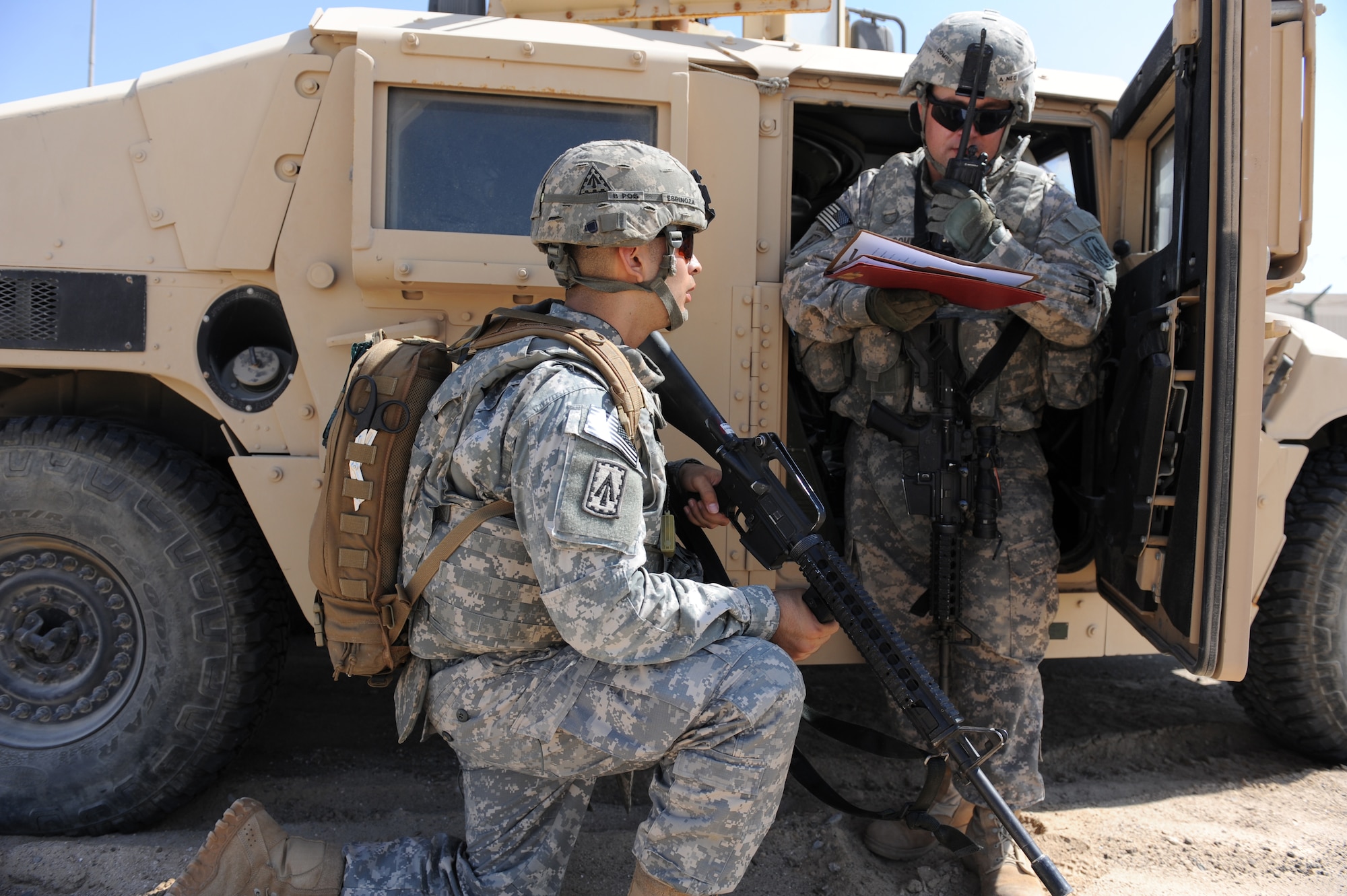 Army Staff Sgt. Brandon Combs, the NCO in charge of force protection for the 3rd Battalion, 4th Air Defense Artillery Regiment, calls in a report following an improvised explosive device incident during convoy training Oct. 28, 2011, at the 380th Air Expeditionary Wing. Spc. Josiah Espinoza, a 3-4 ADAR medic, stands by on guard. The training covered threat response for things like improvised explosive devices and ambushers as well as wounded-Soldier evacuations and procedures for sending reports up to appropriate channels. (U.S. Air Force photo/Master Sgt. Chance Babin)