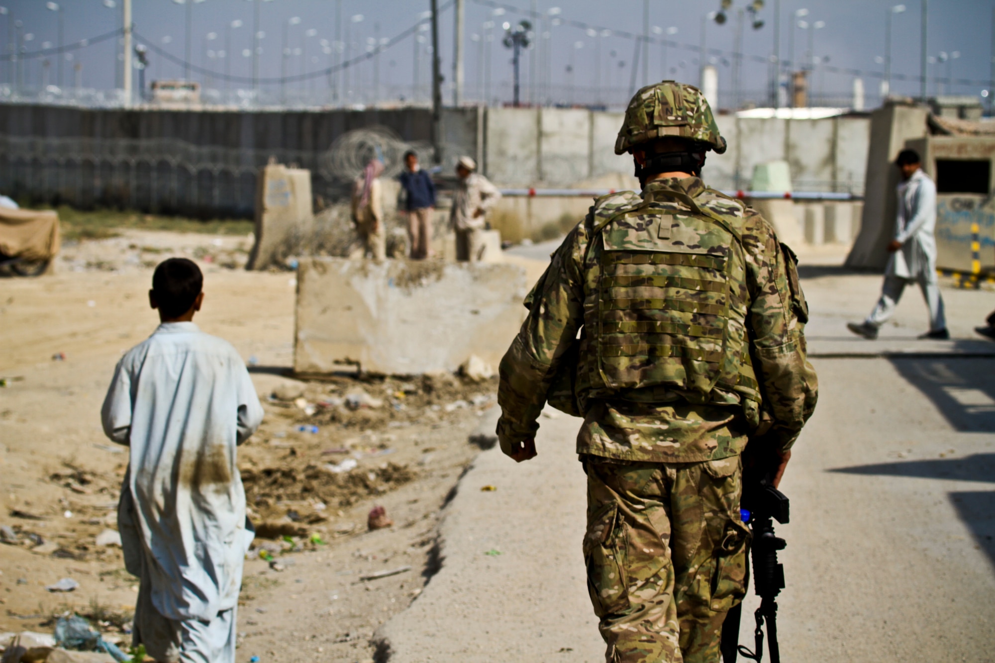 A security forces Airman walks alongside an Afghan child here Oct. 21, 2011. Bagram Airfield is a joint installation, but its security is unusual in that defending the base is performed primarily by Airmen. Airmen from the 455th Air Expeditionary Wing are hard at work each and every day fulfilling the wing’s mission: “Support the fight, defend the base and win.” (U.S. Air Force photo/Tech Sgt. Matthew Hecht)