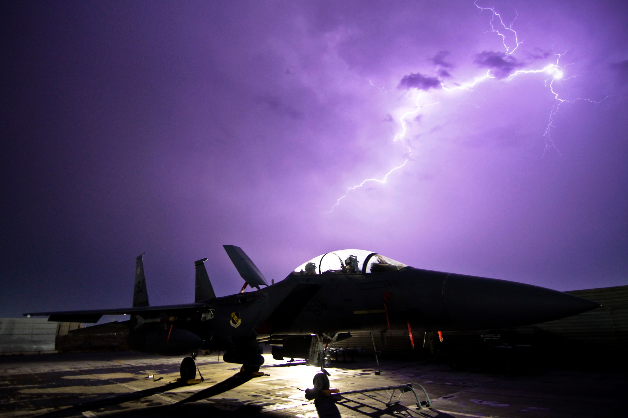 Lighting illuminates the sky behind an F-15E Strike Eagle Oct. 6. 2011. F-15s help provide residual base defense. Bagram Airfield is a joint installation, but its security is unusual in that defending the base is performed primarily by Airmen. Airmen from the 455th Air Expeditionary Wing are hard at work each and every day fulfilling the wing’s mission: “Support the fight, defend the base and win.” (U.S. Air Force photo/Tech Sgt. Matthew Hecht)