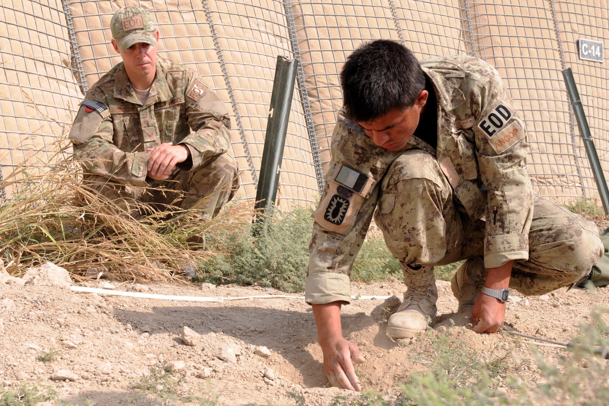 U.S. Air Force Staff Sgt. Kelly Badger, explosive ordnance disposal technician with the 466th Air Expeditionary Squadron, observes Sgt. Nasrullah Mohammad Sharif, Afghan National Civil Order Police EOD technician and sergeant of engineers, as he attempts to locate a buried simulated improvised explosive device during training, Oct. 23, 2011. Badger and his team conduct real-world training with the ANCOP at least once a week, in between partnered missions outside of Combat Outpost Talukan, Panjwa'i district, Kandahar province. (U.S. Army photo by Staff Sgt. Lindsey Kibler, ISAF Joint Command Public Affairs)