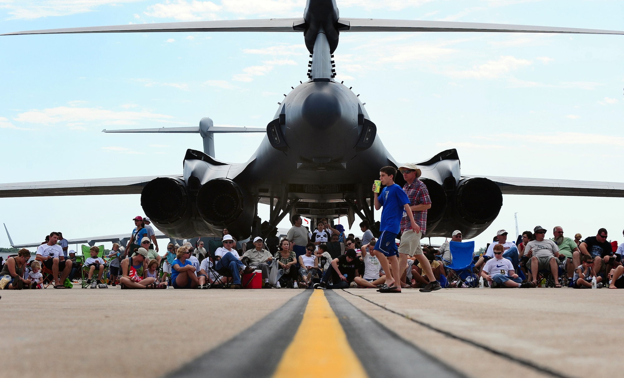 Air show attendees take refuge in the shade of a B-1B Lancer while attending the 2011 Defenders of Freedom Open House and Air Show at Offutt Air Force Base, Neb. Aug 27.  The B-1B is the backbone of America's long-range bomber force and it can rapidly deliver massive quantities of precision and non-precision weapons against any adversary, anywhere in the world, at any time. (U.S. Air Force photo by Josh Plueger)