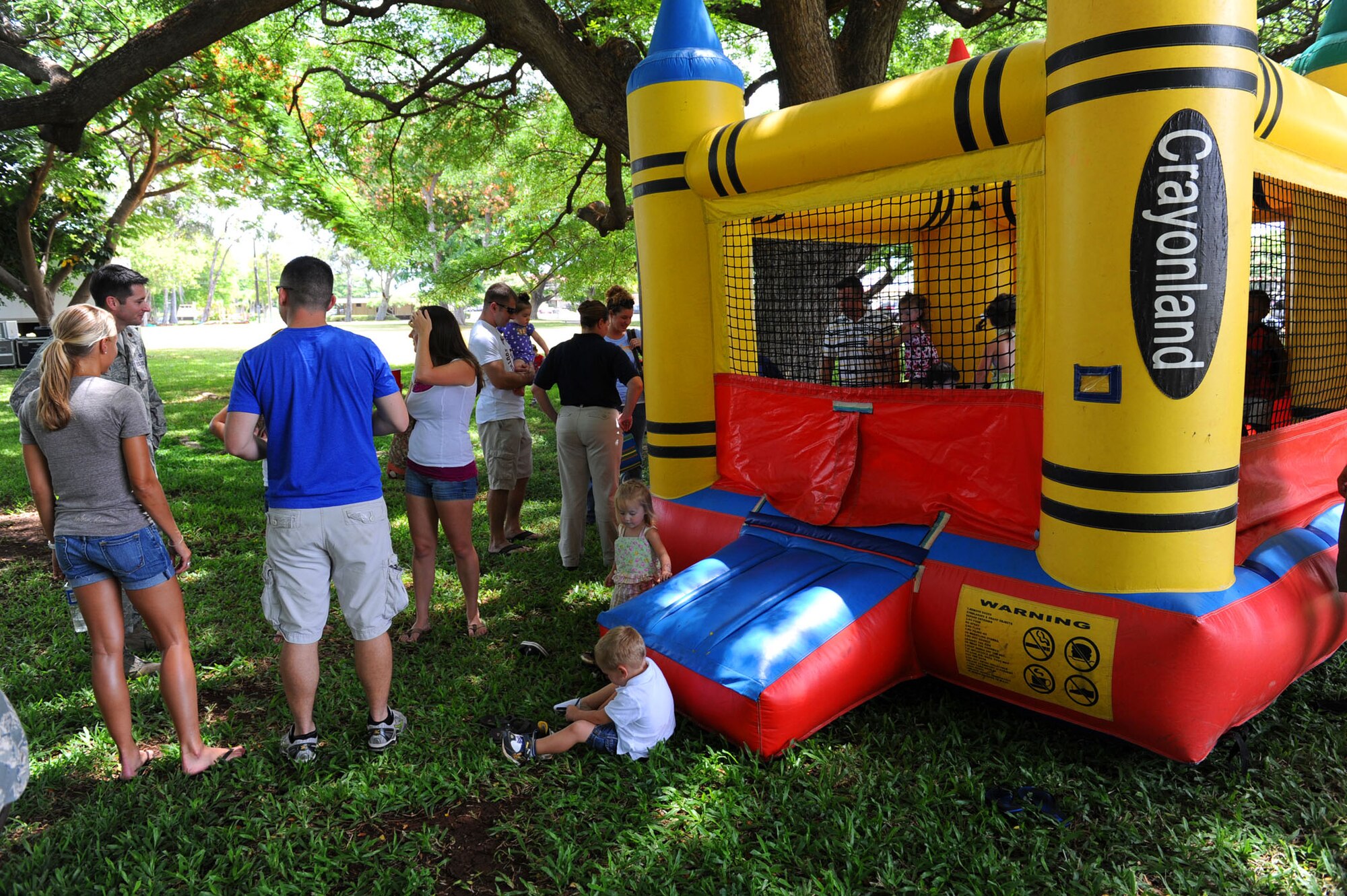 Pacific Air Forces Airmen and their families talk, while their children play and enjoy the day in a Crayon Land bouncy house during Mahalo Bash 2011, at Joint Base Pearl Harbor-Hickam, Sept. 1.  The Mahalo Bash is an annual event hosted by the Pacific Air Forces commander to thank Airmen and their families for their service and hard work throughout the year. (U.S. Air Force photo/Tech. Sgt. Jerome S. Tayborn (Released))