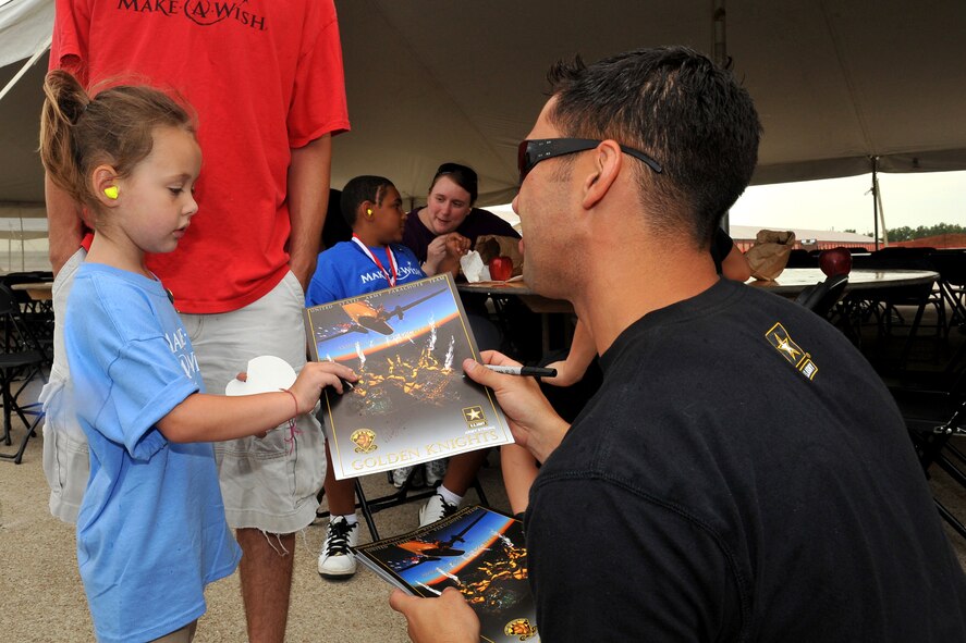 Wish sibling Keegan Rine, sister of Wish child McKinzie Rine, receives a signed Golden Knight's booklet from U.S. Army Staff Sgt. Howard Sanborn during the 2011 Defenders of Freedom Special Needs Air Show at Offutt Air Force Base, Neb., Aug. 26. Sanborn is an airborne infantryman serving as a demonstration parachutist on the U.S. Army's Golden Knights black team. (U.S. Air Force photo by Charles Haymond)