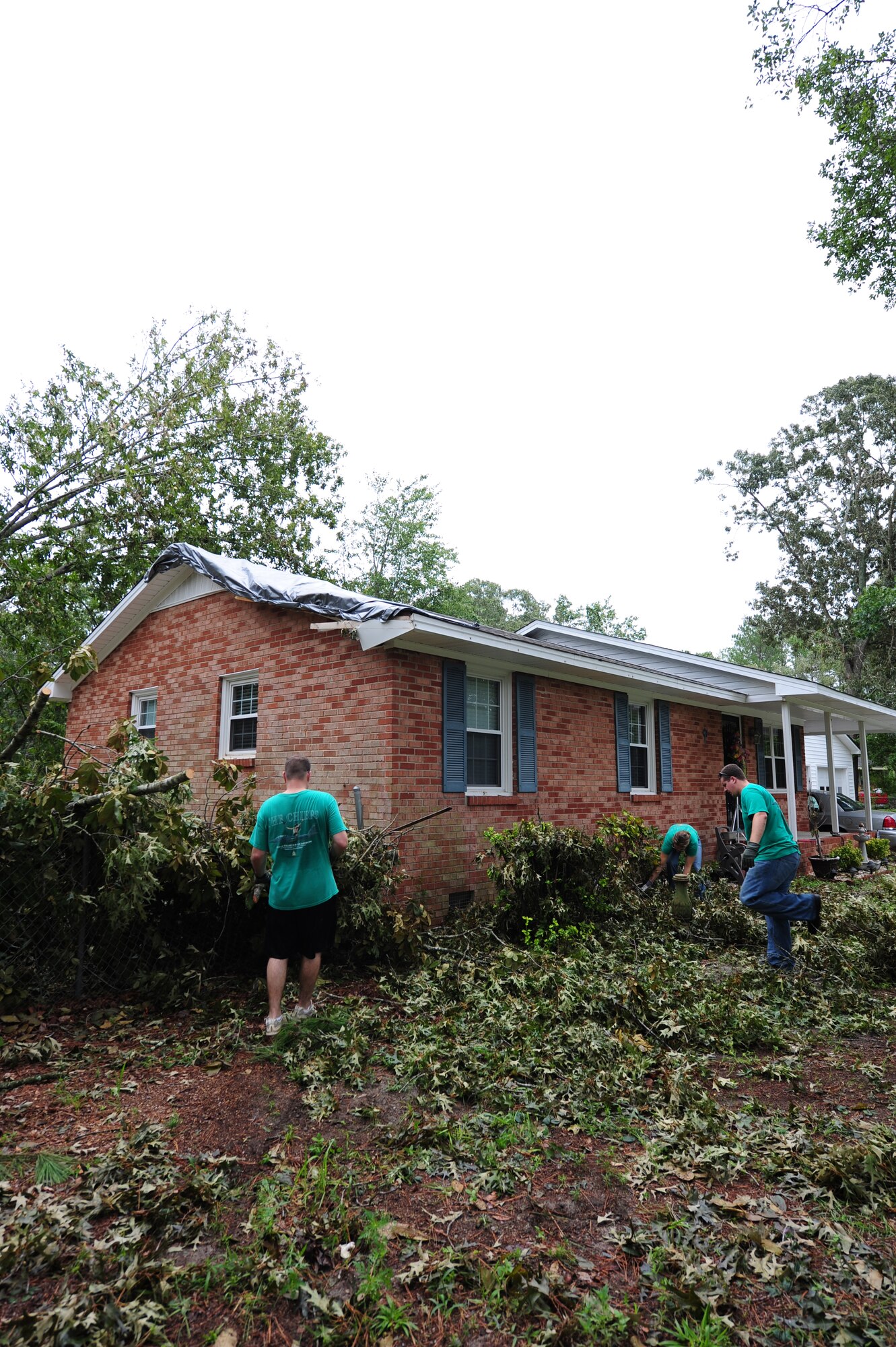Aircrew members from the 335th Fighter Squadron work to remove debris from a tree that struck the house of Willie and Darlene Sparks after Hurricane Irene roared through Goldsboro, N.C., Aug. 30, 2011. The Sparks family worked alongside the members of the 335th FS from Seymour Johnson Air Force Base to clean up their storm ravaged yard. (U.S. Air Force photo by Senior Airman Rae Perry /Released)