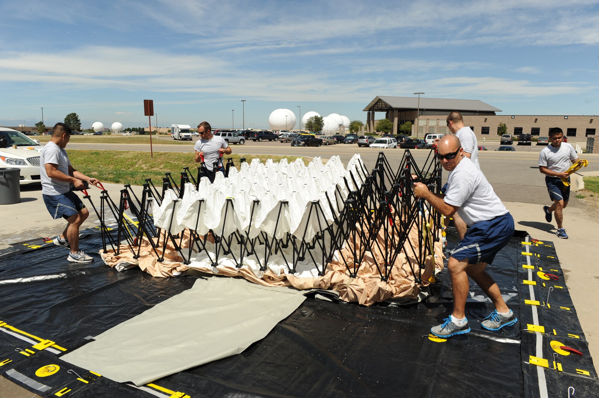 BUCKLEY AIR FORCE BASE, Colo. -- Members of the 460th Medical Group raise an articulating frame shelter as part of in place patient decontamination (IPPD) training on Aug. 18, 2011. The goal of this training is to allow the IPPD team to be mission capable, able to receive and triage patients within fifteen minutes, and fully functional within twenty minutes of an emergency. (U.S. Air Force photo by Airman 1st Class Phillip Houk)
