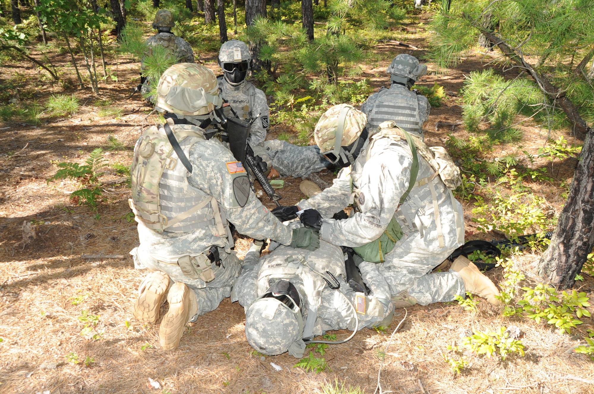 Medics treat an injured Soldier while squad members provide security during a training exercise Aug. 23, at Joint Base McGuire-Dix-Lakehurst. Soldiers hit by Close Combat Mission Capability Kit System dye-marker munitions, can clearly identify the injured area, allowing for immediate administering of “first aid," (U.S. Air Force photo by Pascual Flores/Released)