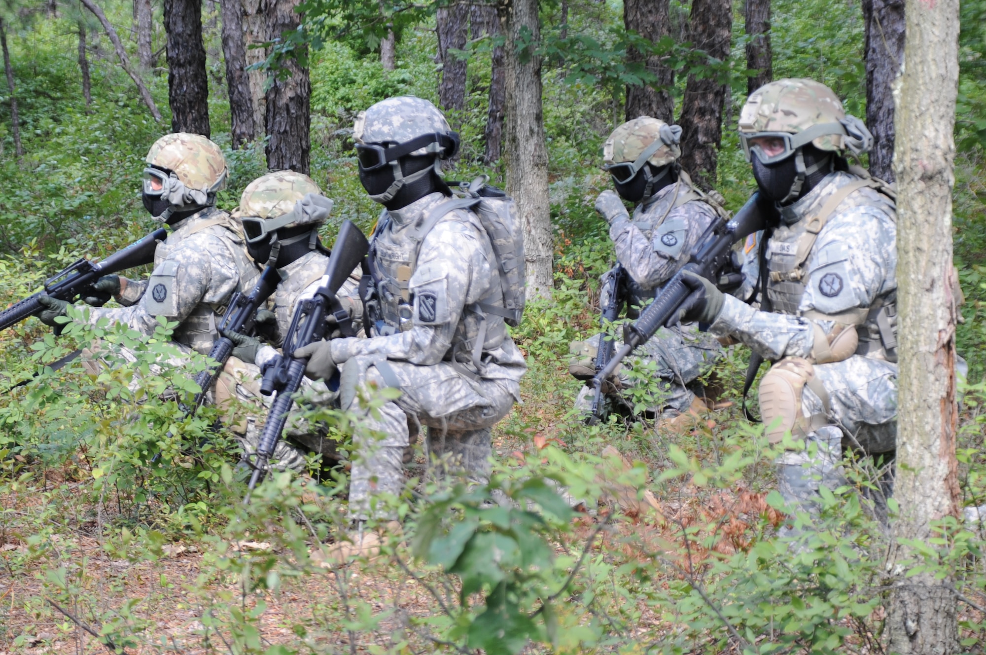 A squad of Soldiers assume protective posture as the squad leader communicates with its’ higher headquarters during a training exercise conducted Aug. 23 at Joint Base McGuire-Dix-Lakehurst. Training with the Close Combat Mission Capability Kit System allows Soldiers to train in realistic urban and close-combat mission scenarios. (U.S. Air Force photo by Pascual Flores/Released)