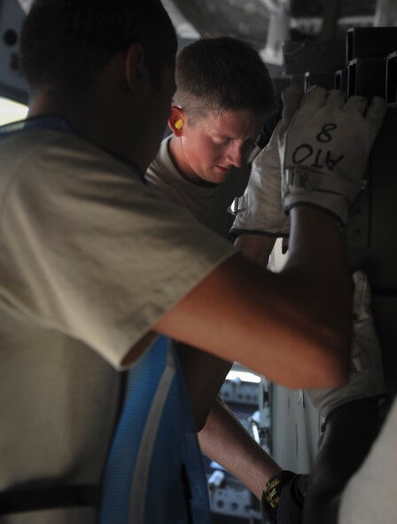 U.S. Air Force Airman 1st Class Timothy Barnwell, 23rd Logistics Readiness Squadron air transportation craftsman, and Staff Sgt. Christopher Caffee, 23rd LRS flight dispatch, push a crate of gear onto the back of a C-17 Globemaster III aircraft at Moody Air Force Base, Ga., Aug. 26, 2011. The crew had to load the crates into specific spots to ensure an even balance of weight on the aircraft. (U.S. Air Force photo by Airmen 1st Class Nicholas Benroth/Released)