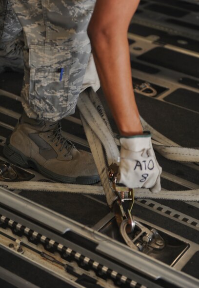 A cargo strap is tightened down as members of the 23rd Logistics Readiness Squadron load gear in preparation for a 38th Rescue Squadron deployment at Moody Air Force Base, Ga., Aug. 26, 2011. Loaders strapped the gear down to ensure no equipment would shift during the flight. (U.S. Air Force photo by Airmen 1st Class Nicholas Benroth/Released)