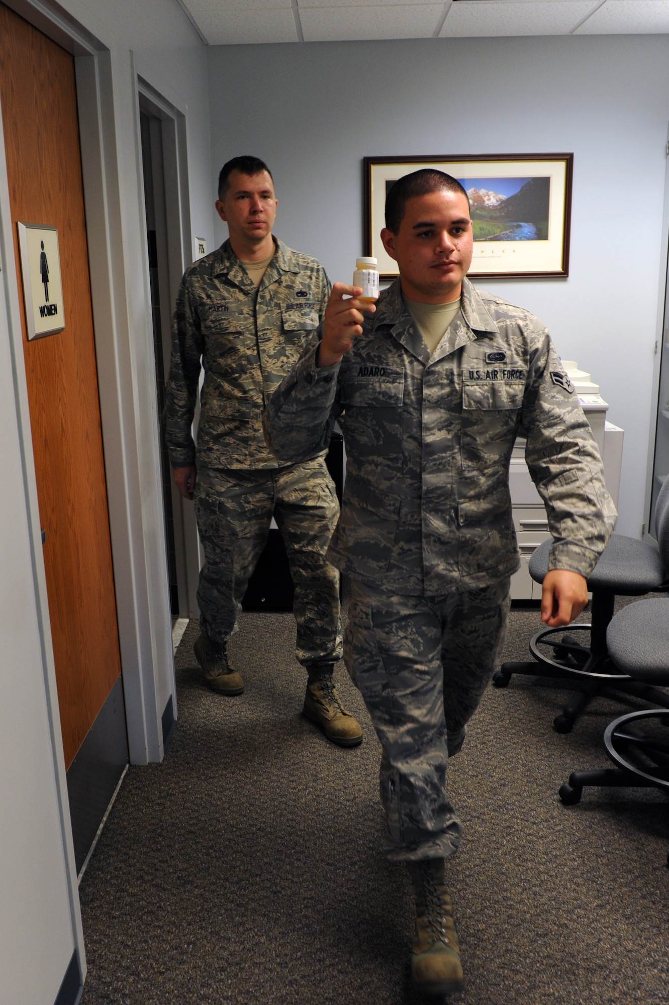 A Team Little Rock member is escorted out of the restroom by Staff Sgt. Lee Martin, a urinalysis observer after providing a urine sample Aug. 30, 2011, at Little Rock Air Force Base, Ark. Members of the Drug Demand Reduction Program team, along with administering urinalysis, also can search squadron and dormitories for drugs. (U.S. Air Force photo by Airman 1st Class Rusty Frank)