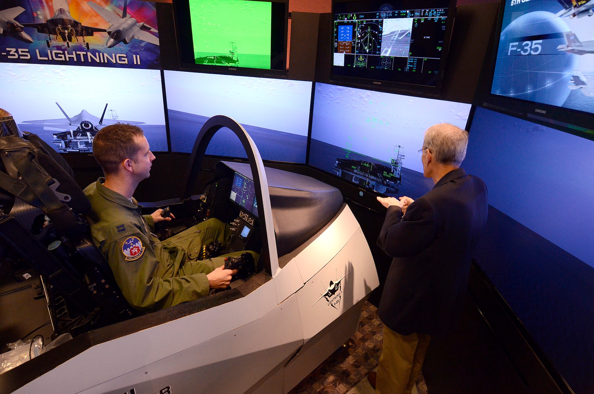 Mr. Mike Skaff, chief engineer of pilot/vehicle interface for the F-35 program, assists Capt. Jonathan Lester, a C-130 pilot from the 700th Airlift Squadron at Dobbins Air Reserve Base, in landing aboard an aircraft carrier, 31 Aug.  Lockheed Martin held a special event for the press and invited guests at the Marietta facility with their F-35 Joint Strike Fighter cockpit demonstrator as the focal point.  (U.S. Air Force photo/ Brad Fallin)