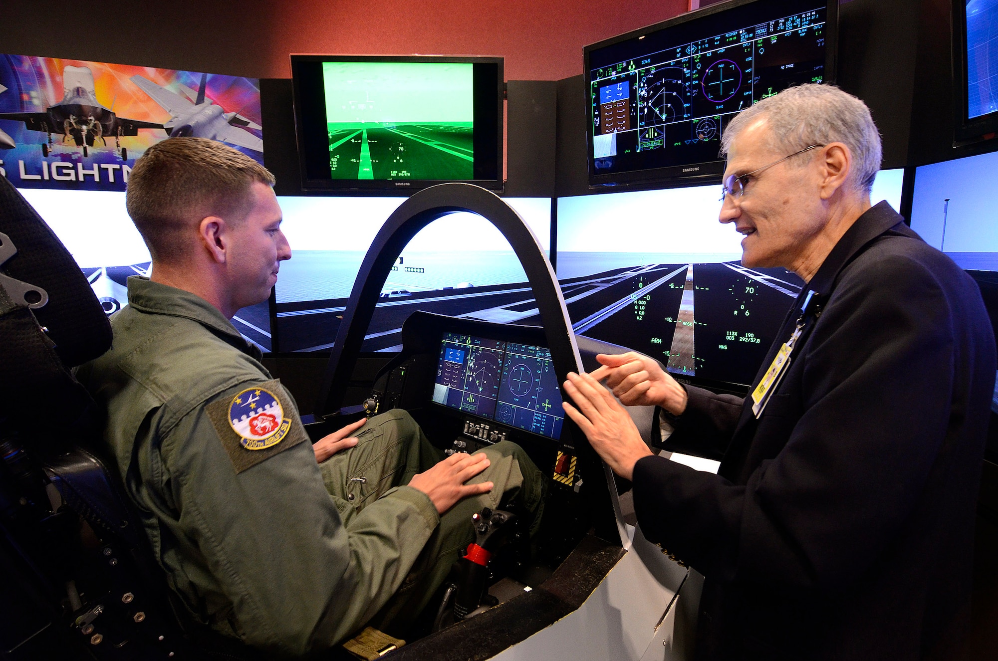 Senior Airman Michael Sterchi, a C-130 Loadmaster from the 700th Airlift Squadron, listens to Mr. Mike Skaff, chief engineer of pilot/vehicle interface for the F-35 program, for some pointers on flying an F-35C off the carrier, 31 Aug.  Lockheed Martin held a special event for the press and invited guests at the Marietta facility with their F-35 Joint Strike Fighter cockpit demonstrator as the focal point.  (U.S. Air Force photo/ Brad Fallin)