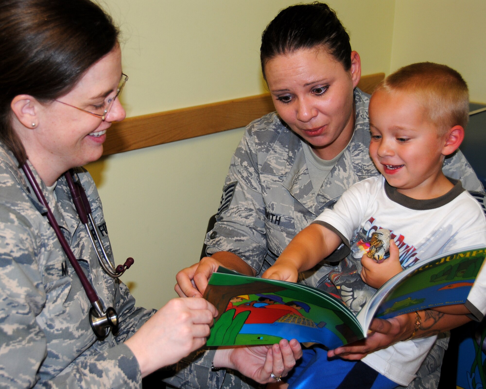 Capt. (Dr.) Kimberly Milford, left, reads with Jason Smith, right, and his mother, Tech. Sgt. Kelli Smith, in the 71st Medical Group Pediatrics Clinic at Vance Air Force Base, Okla. They are participating in “Reach Out and Read,” a new literacy program that is part of regular appointments at the clinic. (U.S. Air Force photo/ Zach Sproul)