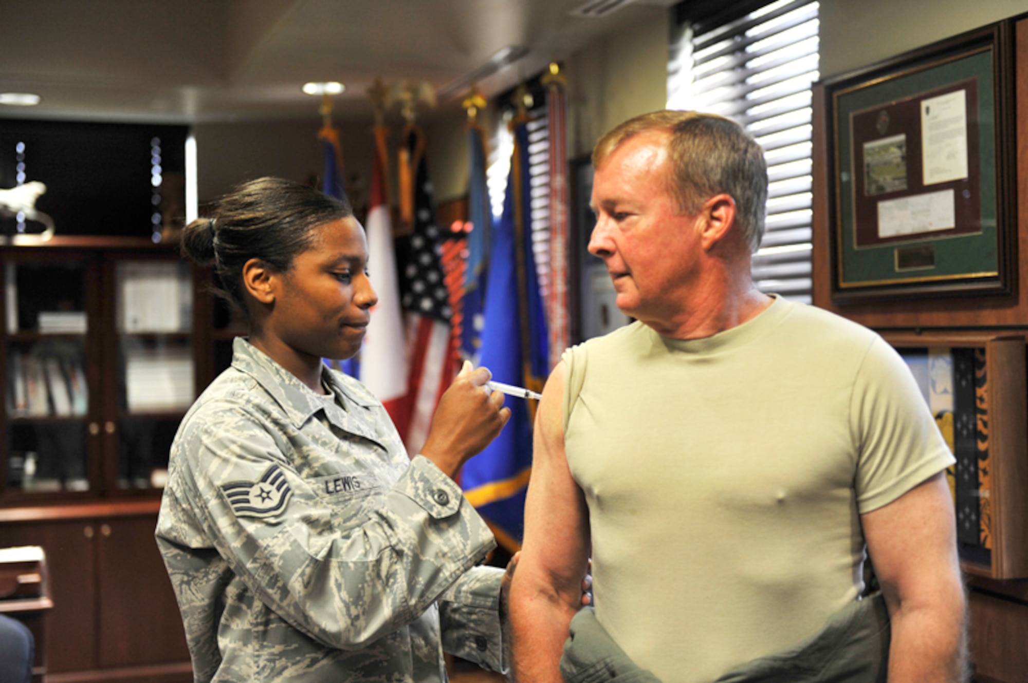 Air Force Lt. Gen. Dana Atkins receives an influenza vaccination on Joint Base Elmendorf-Richardson at the Alaskan Command building by Tech. Sgt. Alexis Lewis, independent duty medical technician, 673rd Aerospace Medical Squadron, Aug. 24. General Atkins is the commander for Alaskan Command, 11th Air Force, and Alaskan North American Defense Region. (U.S. Air Force photo/Airman 1st Class Ty-Rico Lea)