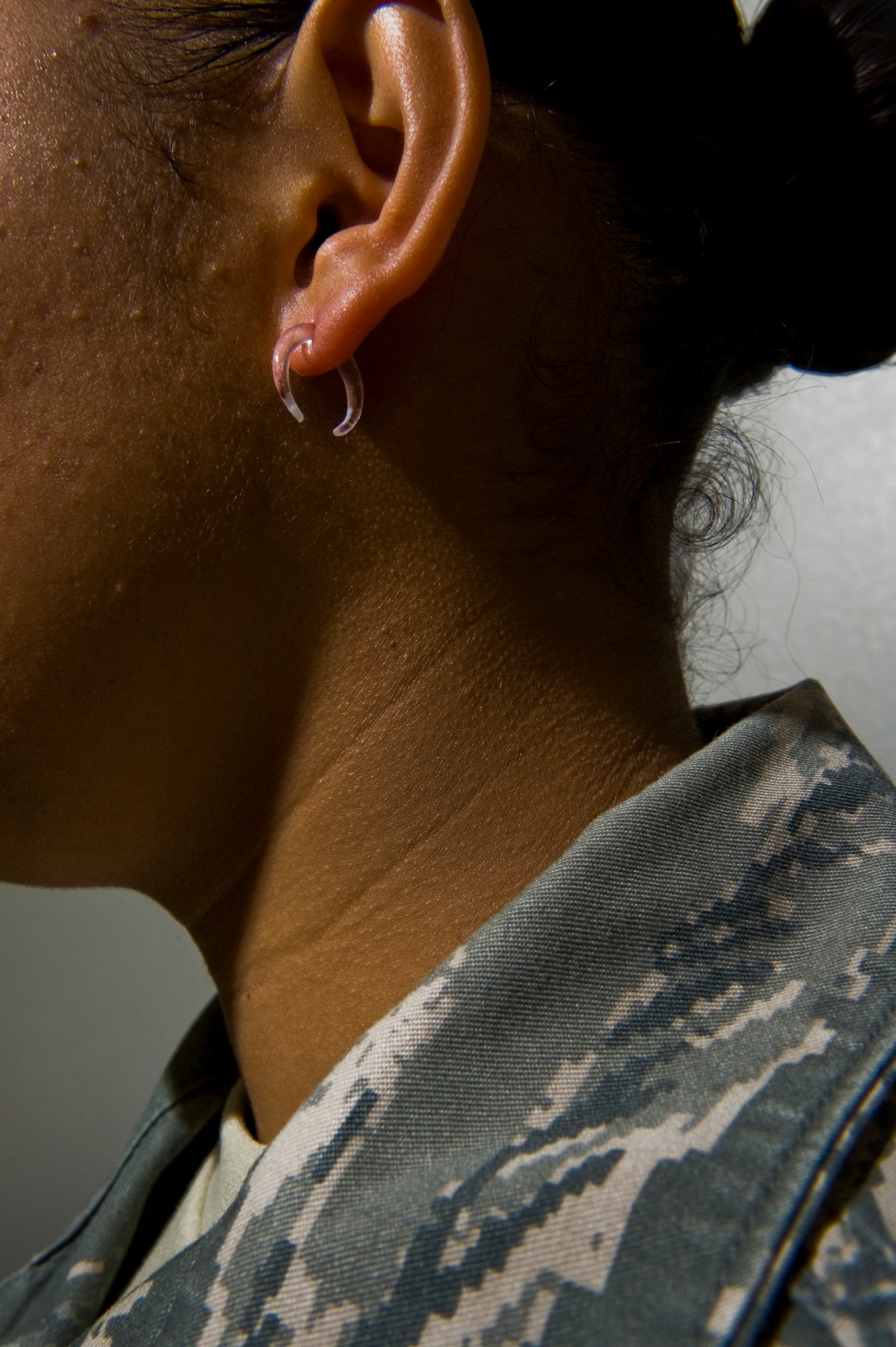 U.S. Air Force Airman wears unauthorized earrings to work Aug. 30, 2011, at Nellis Air Force Base, Nev. The new Air Force Instruction 36-2903, which was revised July 13, 2011, states Airmen may wear small (not exceeding 4mm in diameter) spherical, conservative (moderate, being within reasonable limits; not excessive or extreme) round white diamond, gold, white pearl, or silver earrings as a set with any uniform combination. (U.S. Air Force photo by Airman 1st Class Daniel Hughes/Released)
