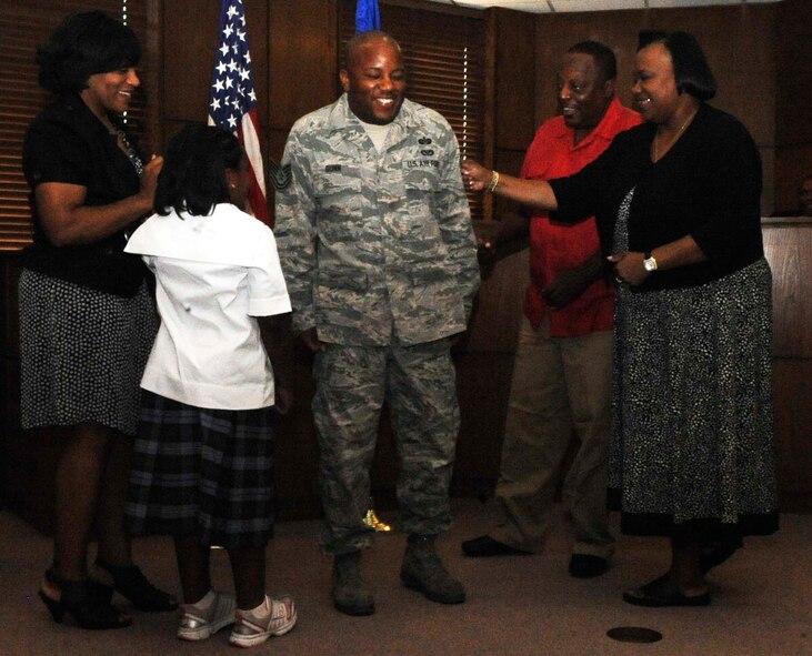 Staff Sgt. Geoffery Gunn, 2nd Bomb Wing Legal Office, braces himself for the impact before his family "tacks" on his technical sergeant stripes during his promotion ceremony on Barksdale Air Force Base, La., Aug. 31. Gunn's wife, daughter and parent's attended the ceremony, while his younger sister viewed the ceremony via video teleconference from her deployed location in Southwest Asia.  (U.S. Air Force photo/Staff Sgt. Terri Barriere) (RELEASED)