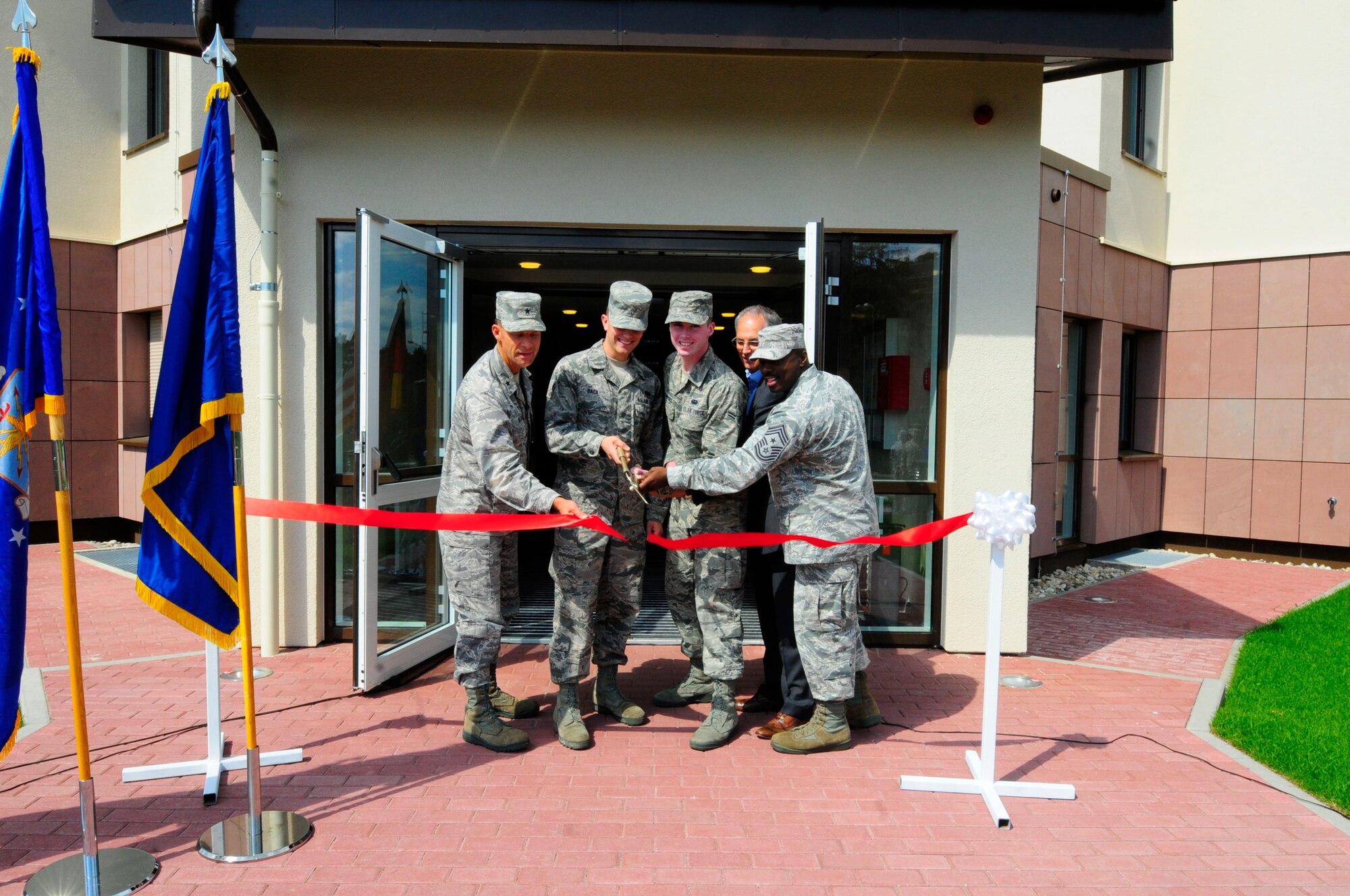 Airmen and leadership from the 86th Airlift Wing cut a ribbon during a ribbon cutting ceremony to mark the completion of the new "Dorms 4 Airmen" dormitory built on Ramstein Air Base, Germany, Aug. 31, 2011. The new building has four floors, 8 apartments per floor, and can hold 128 Airmen. (U.S. Air Force photo by Airman 1st Class Kendra Alba) 