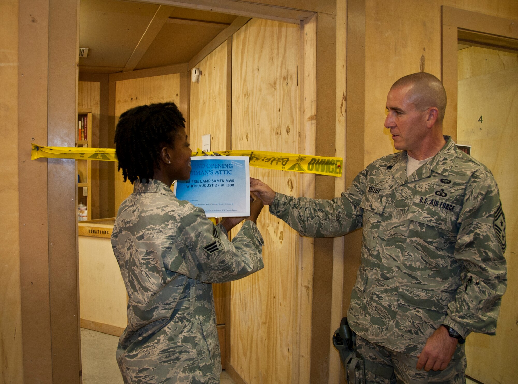 Senior Airman Lethacha Henderson, First Four Airman's Council president, and Chief Master Sgt. Thomas Vallely, 451st Air Expeditionary Wing command chief, cut the ribbon during the grand opening of the Airman's Attic grand opening at the Camp Samek recreation center Aug. 27, 2011. The attic will be open to servicemembers from 9 a.m. to 9 p.m. seven days a week. (U.S. Air Force photo by Senior Airman David Carbajal)