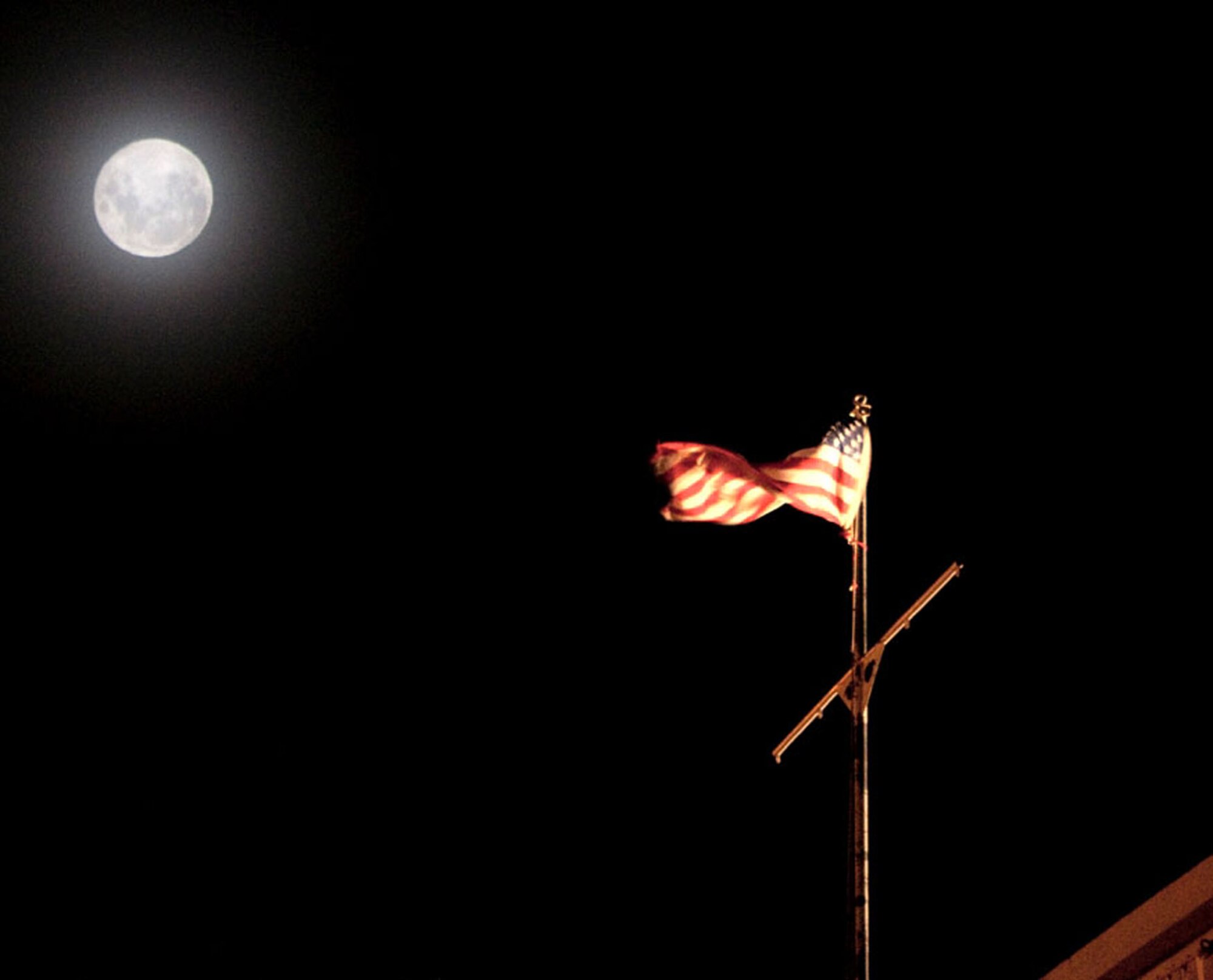 The Antarctic full moon shines on the stars and stripes flying over McMurdo Station. Chief Master Sgt. Michael Beck was able to fly the flag while there for eight months, and will bring it home with him when he returns this month. He was deployed with his civilian employer, and is the Fire Chief with the 349th Civil Engineer Squadron at Travis AFB. (Courtesy photo)
