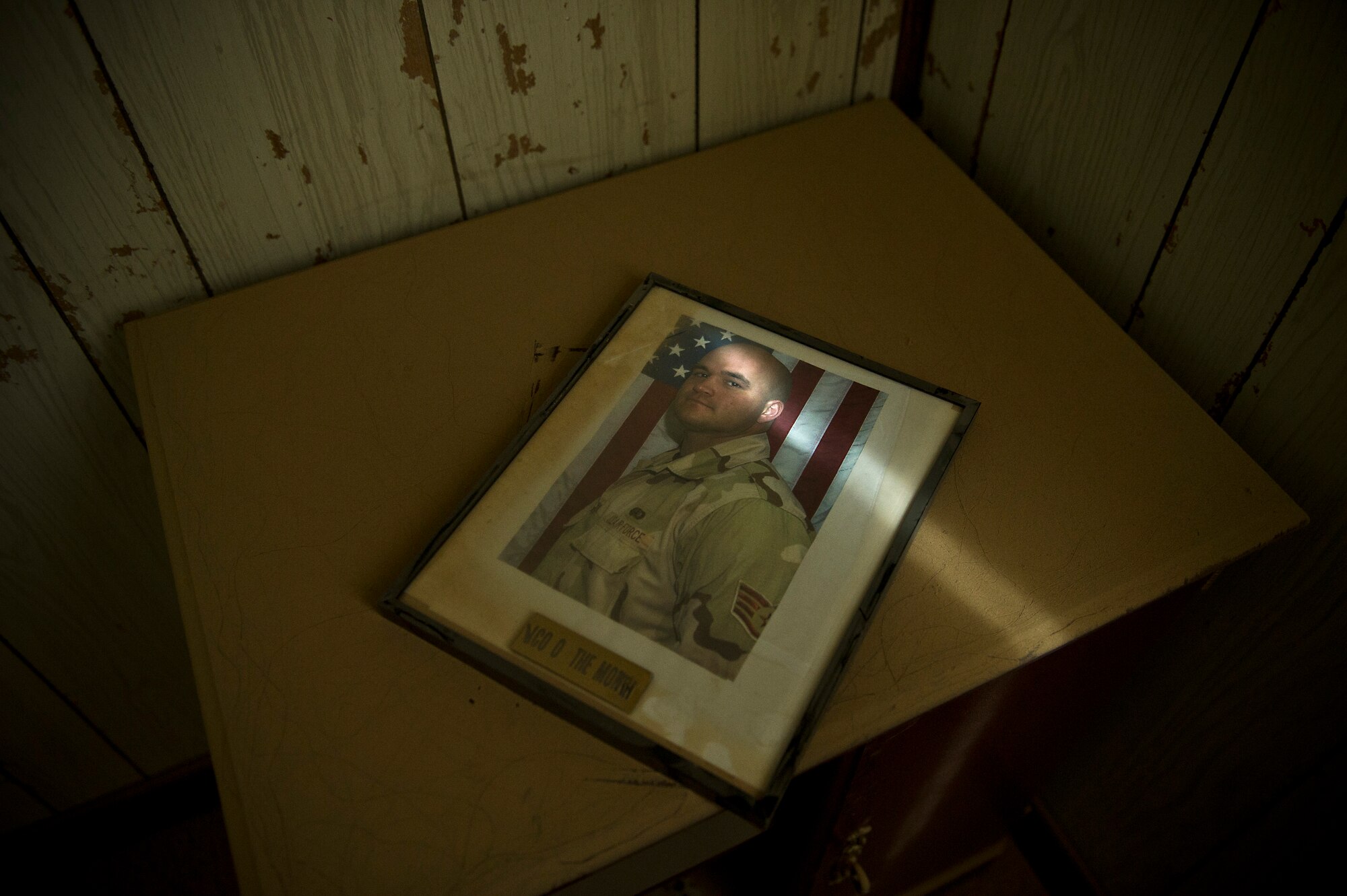 A photo of an award winner rests on a desk, Aug. 29,2011 at an undisclosed location in Southwest Asia.  Photos of past award winners can be found in abandon office buildings at a base in Southwest Asia. The offices have been abandon since the U.S. Air Force closed the base several years ago. A team of Airmen are opening the base to support Operation New Dawn. (U.S. Air Force Photo/Master Sgt. Jeffrey Allen)