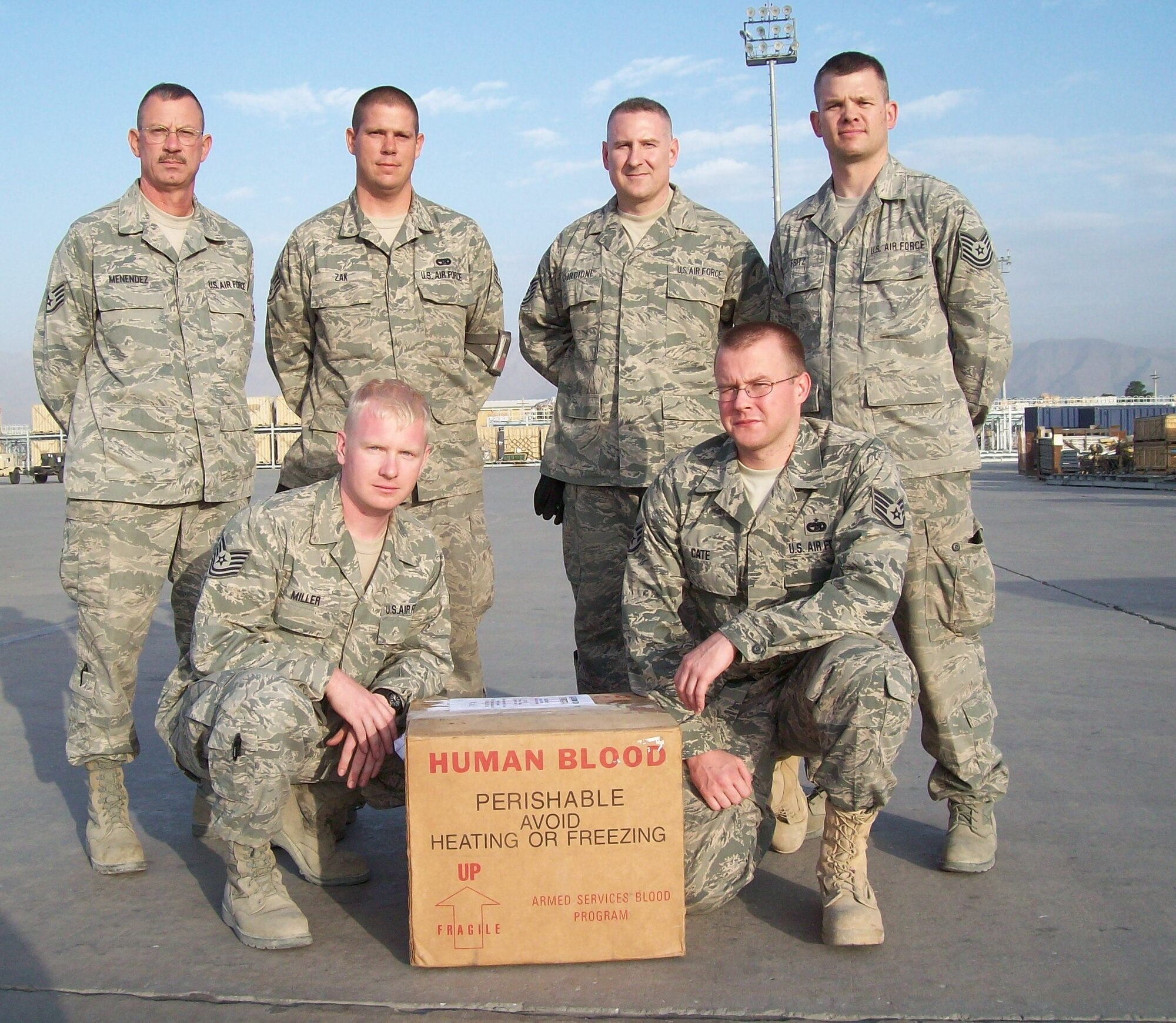914th Airlift Wing Airmen deployed with the 455th Expeditionary Aerial Port Squadron stand near the flight line at an undisclosed location in southwest Asia. The Reserve Airmen were responsible delivering blood across the country to U.S. Soldiers who were in critical condition and in desperate need of it earlier this month. (Courtesy Photo)