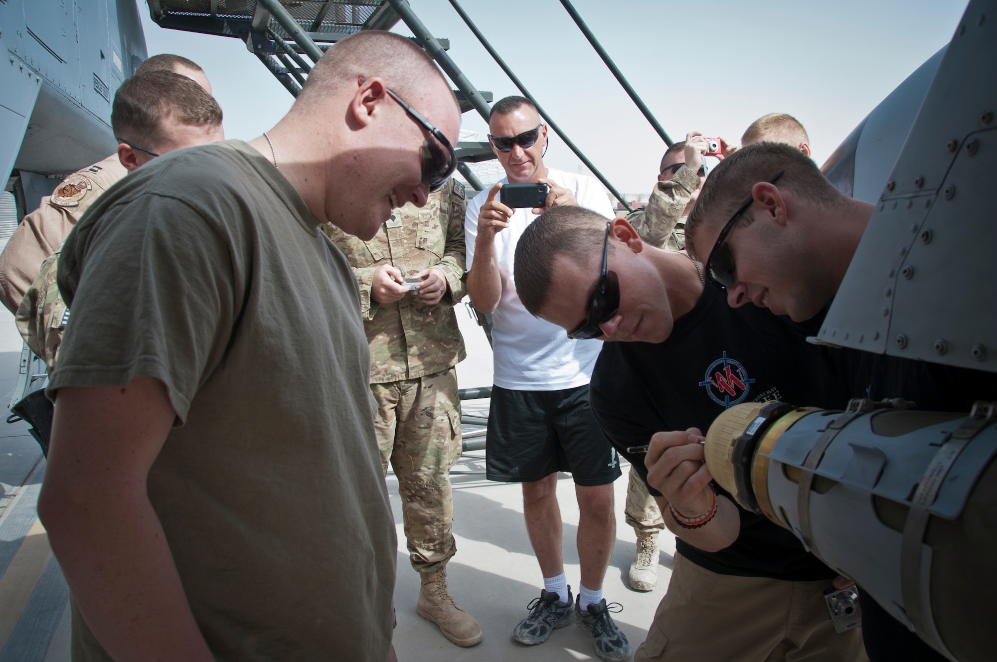 KANDAHAR AIRFIELD, Afghanistan -- Several wounded warriors sign one of the joint direct attack munitions during a tour of the 74th Expeditionary Fighter Squadron's A-10 Thunderbolt IIs Aug. 29, 2011. The 74th EFS is deployed from Moody Air Force Base, Ga. (U.S. Air Force photo by Senior Airman David Carbajal)