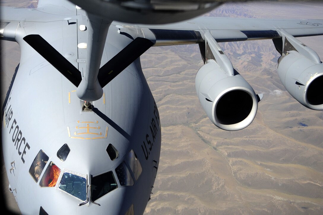 Aircrew members hold American and Kyrgyz Republic flags in the windows of a C-17 Globemaster III as it is refueled by a KC-135 Stratotanker during an aerial refueling orientation flight Sept. 2. The orientation flight was designed to showcase aerial refueling procedures to key personnel at the Kyrgyz Ministry of Transportation and Communication, the Civil Aviation Agency, the Manas International Airport and the Kyrgyz Air Navigation military sector. The aircraft and crews are assigned to the Transit Center at Manas, Kyrgyzstan. (U.S. Air Force photo/Tech. Sgt. Tammie Moore)