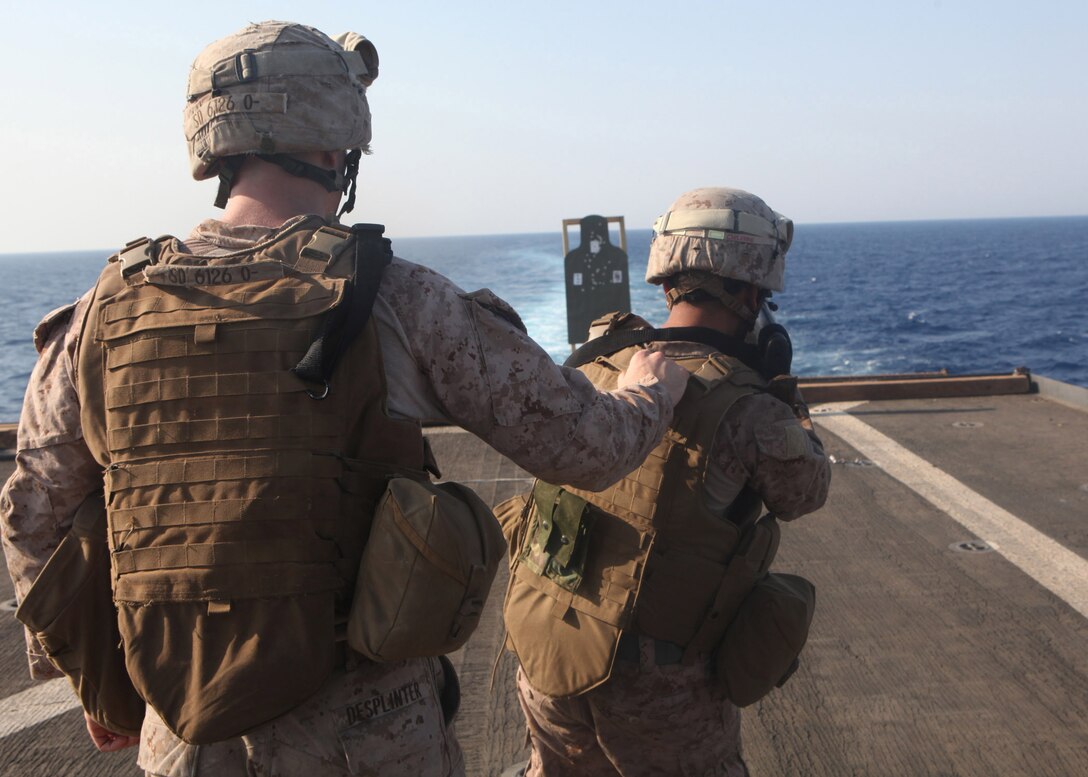 Cpl. Seth J. Desplinter, left, a squad leader with Echo Company, Battalion Landing Team, 2nd Battalion, 2nd Marine Regiment, 22nd Marine Expeditionary Unit (MEU), and Kewanee, Ill., native, guides Lance Cpl. Thomas H. Duong, a rifleman with Echo Company, and Jackson, N.J., native, as he fires while moving during a squad timed shoot aboard dock landing ship USS Whidbey Island (LSD 41), Sept. 5. The squad timed shoot incorporates physical activity, positive identification, movement, and marksmanship to improve combat environment reaction time. The 22nd MEU is currently deployed as part of the Bataan Amphibious Ready Group (BATARG) as the U.S. Central Command theater reserve force, also providing support for maritime security operations and theater security cooperation efforts in the U.S. 5th Fleet area of responsibility.