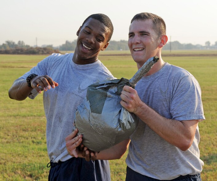 Staff Sgt. Eric Murphy and 2nd Lt. Josh Hight, 2nd Security Forces Squadron, pass a sandbag to one another Sept. 1 during tryouts for the 2 SFS Global Strike Challenge team. The Airmen trying out for the team endure rigorous tests to evaluate their fitness, land navigation skills and marksmanship. (U.S. Air Force photo/2nd Lt. Tori Lalich)(RELEASED)