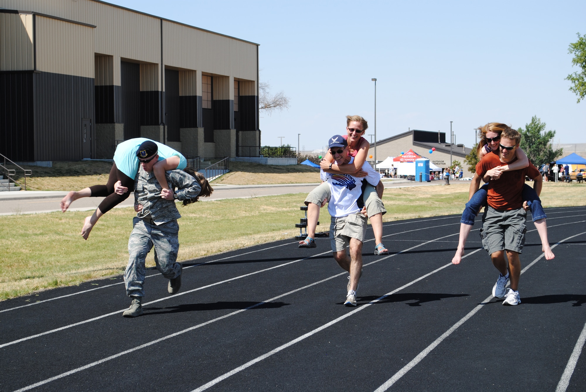 Three teams participate in the wife/girlfriend carry/ From left are 1st Lt. Jeffrey Beene, 341st MIssile Security Forces Squadron CCE and his wife, Erin; Chief Master Sgt. Duane Buchie, 341st Medical Group superintendent, and his wife, Lynn; and Daniel Christian and his wife, Brittany, Buchie's family members. (U.S. Air Force photo/Cortney Paxton)