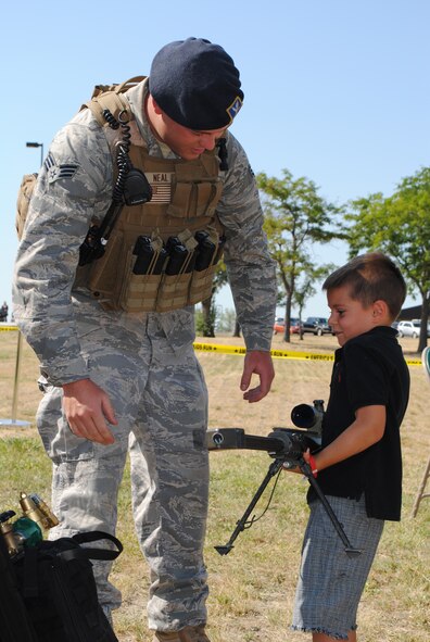 Senior Airman Adam Neal, 341st Security Forces Group tactical response force member, shows Ethan Lopez, 6, how heavy one of the weapons is that TRF members operate. (U.S. Air Force photo/Cortney Paxton)