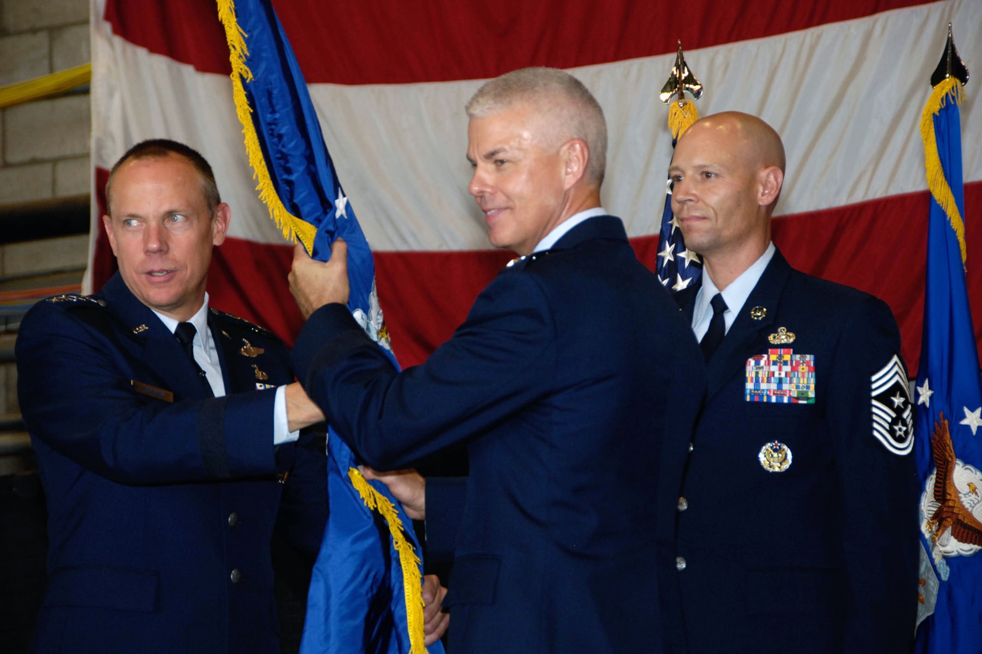 HANSCOM AIR FORCE BASE, Mass. - Lt. Gen. Charles (C.R.) Davis, new Electronic Systems Center commander, accepts the command guidon from Gen. Donald Hoffman (left), Air Force Materiel Command commander, during the change of command ceremony at the Hanscom Aero Club Hangar Sept. 1, while Chief Master Sgt. Kevin Call, ESC command chief, looks on. (U.S. Air Force photo by Linda LaBonte Britt)

