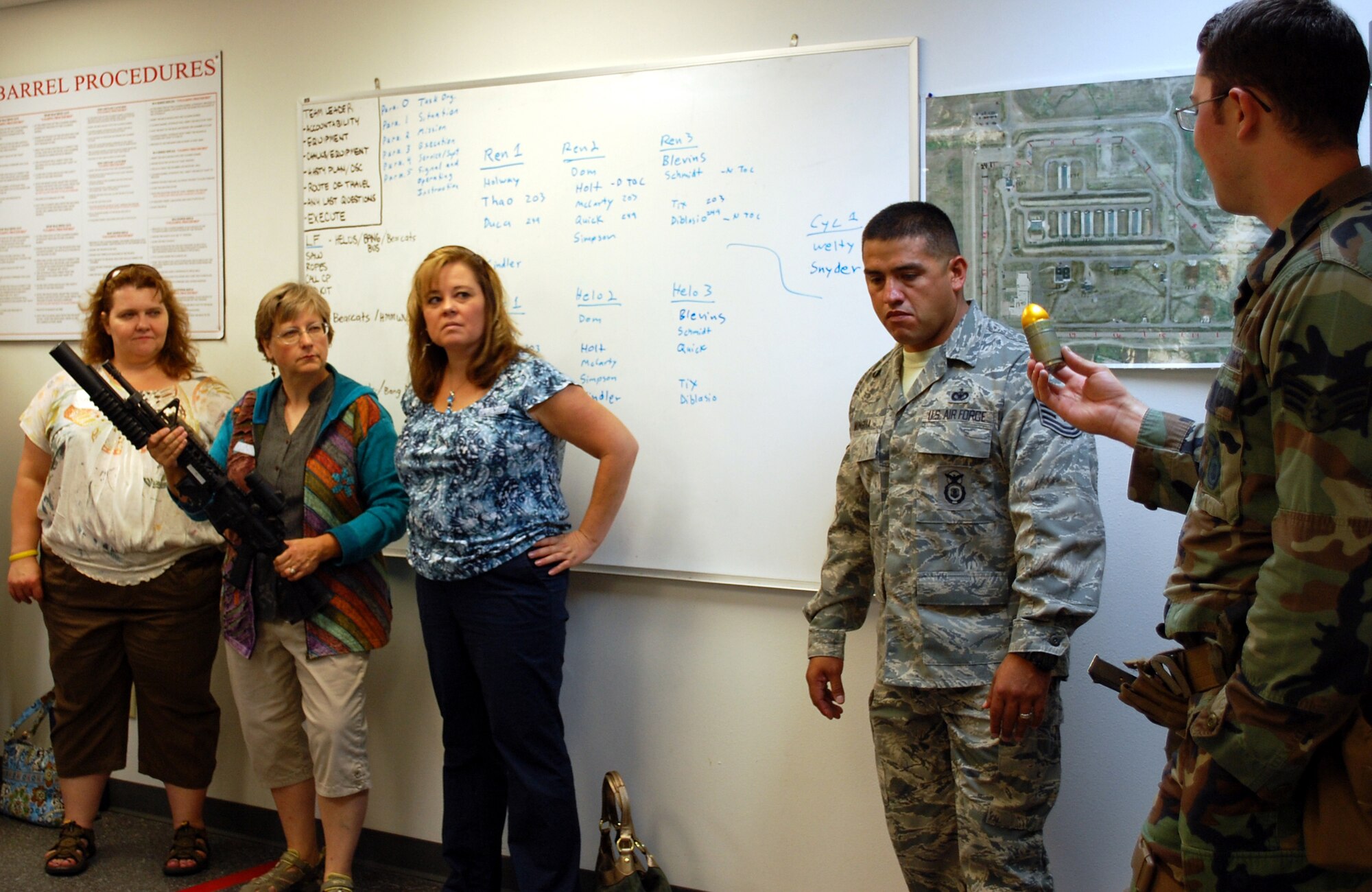 Senior Airman Jason Dominici, a member of the Tactical Response Force, holds up a round of ammunition for the M203 grenade launcher that Loy Elementary teacher Debby Kelly is holding. (U.S. Air Force photo/Valerie Mullett)
