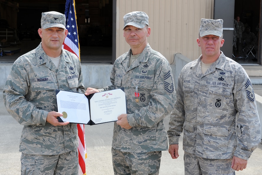 U.S. Air Force Col. Randall Richert, 820th Base Defense Group commander, presents Chief Master Sgt. Larry Miller, 824th Base Defense Squadron, with a Bronze Star Medal certificate at Moody Air Force Base, Ga., Sept. 1, 2011. Chief Miller earned the medal for his work while deployed to Iraq. (U.S. Air Force photo by Senior Airman Ciara Wymbs/Released) 